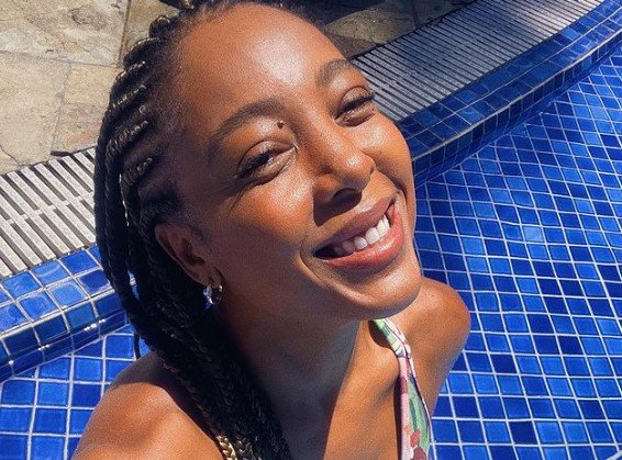 Selfie de Negra Li sorrindo sentada na beira de uma piscina