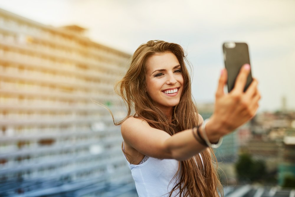 Mulher branca tirando selfie sorrindo