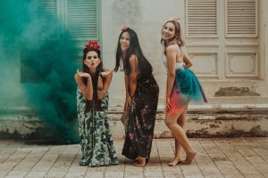 Mulheres dançando ao ar livre e sorrindo.