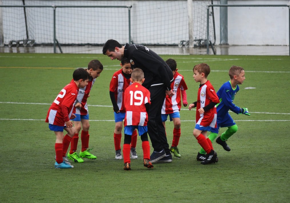 Crianças e treinador em campo de futebol