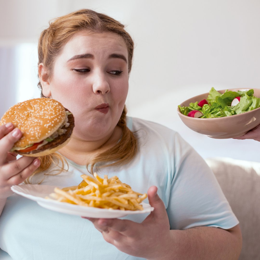 Mulher comendo hamburguer com fritas e pessoa oferecendo salada