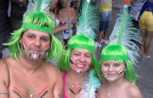 Pai, mãe e filho fantasiados de índio com perucas verdes