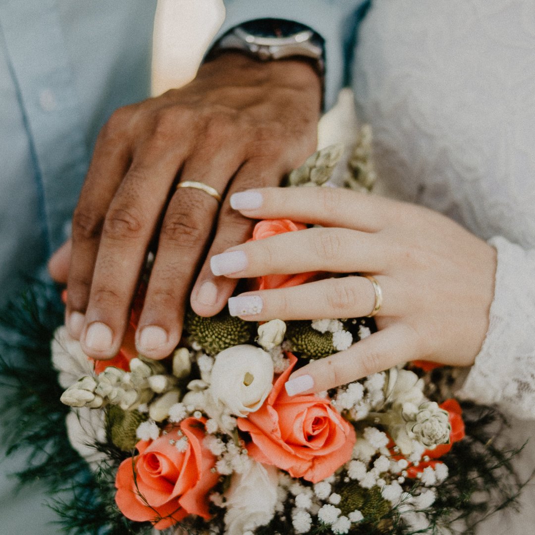 Casal de mãos dadas sob o buquê do casamento