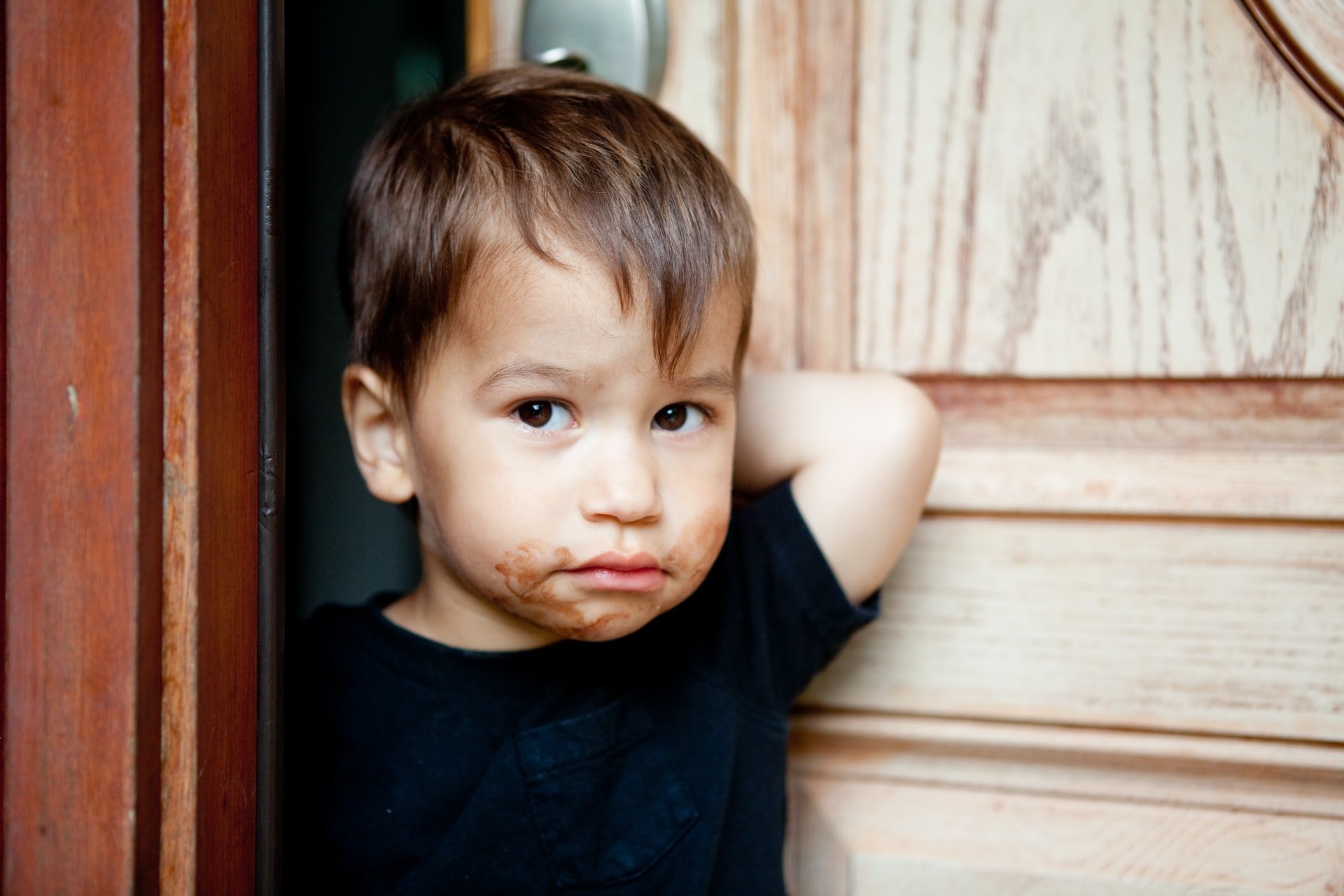 Criança do sexo masculino com a boca e parte do rosto sujo de chocolate