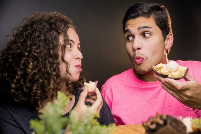 Um homem e uma mulher comendo ovos de páscoas enquanto se olham