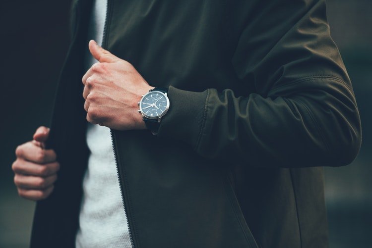 Homem usando relógio de pulso arruma o blazer preto que está vestindo
