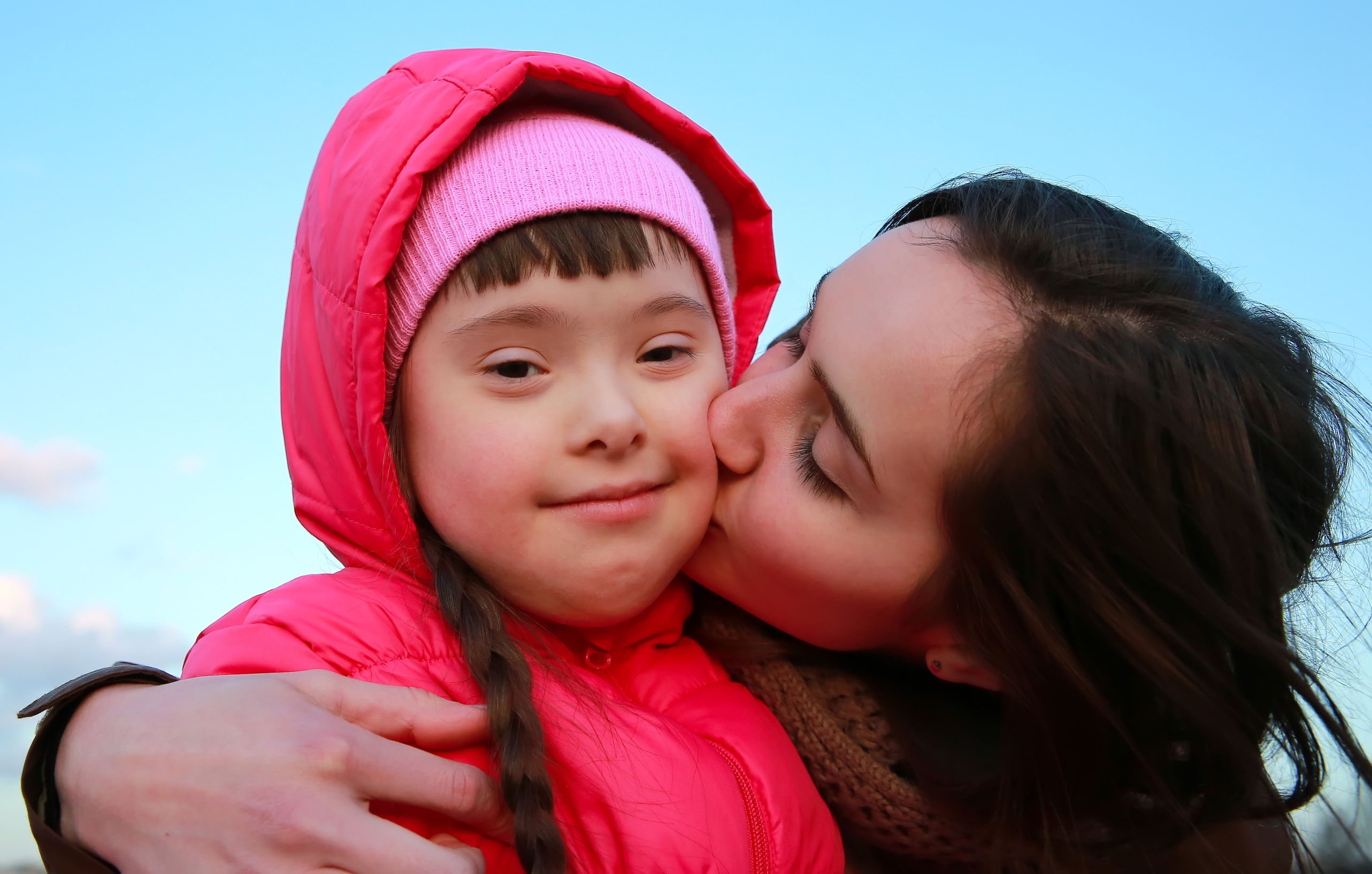 Mãe beijando filha com Síndrome de Down