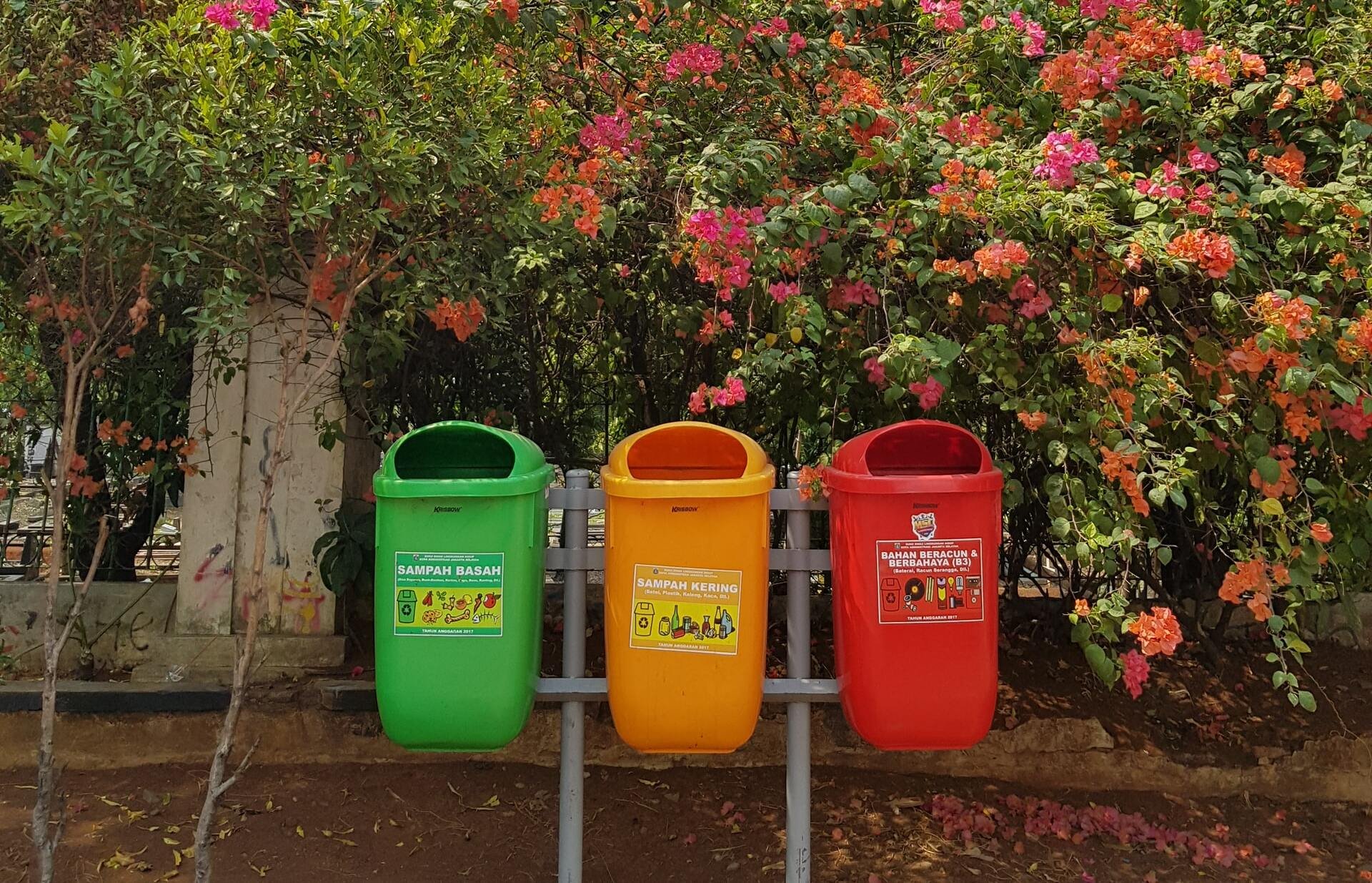 Três latas de lixo nas cores verde, amarela e vermelha.
