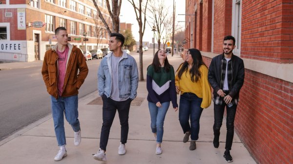 Unsplash | Eliott Reyna Grupo de amigos felizes caminhando em calçada