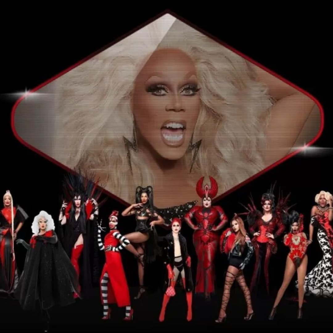Imagem do artista RuPaul em um telão durante o seu show e diversas drag queens na frente do telão