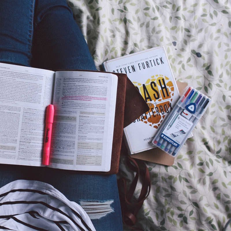 Livro didático e marca-texto rosa no meio