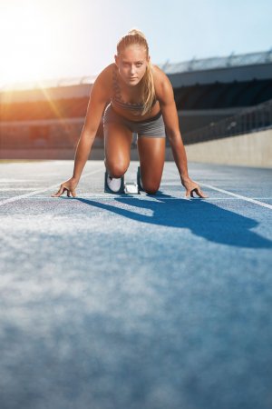 Ammentorp - Dreamstime.com Mulher ajoelhada em pista de corrida, em posição de preparação para correr.