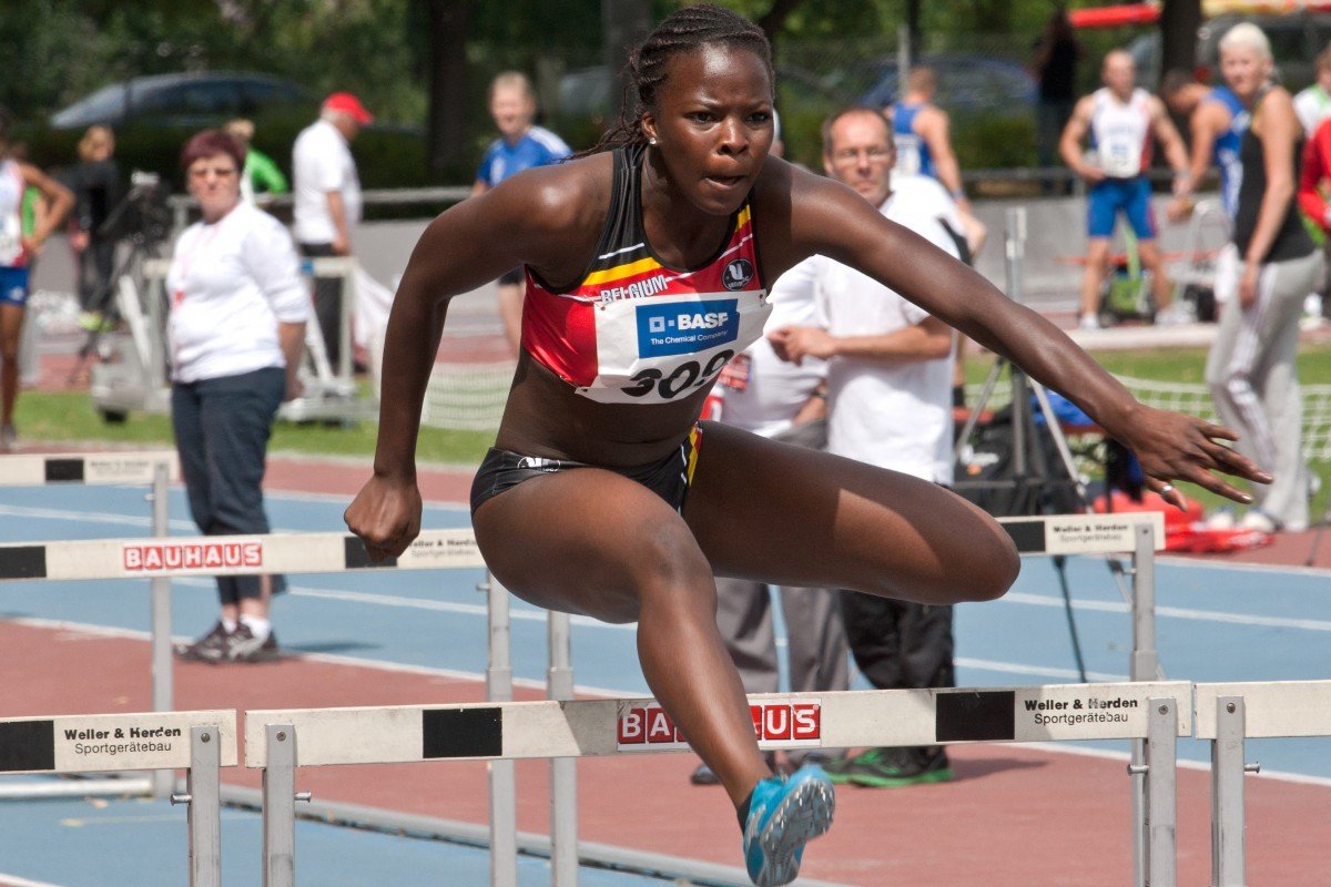 Mulher pulando barreira durante corrida de obstáculos.