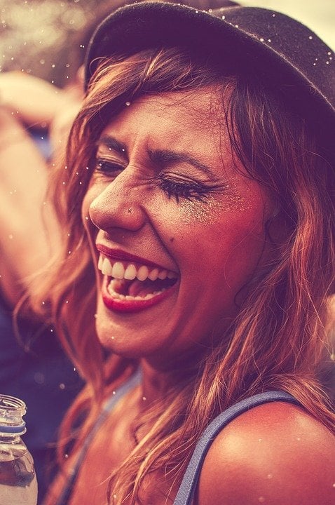 Garota sorrindo com rosto pintado e chapéuzinho de carnaval