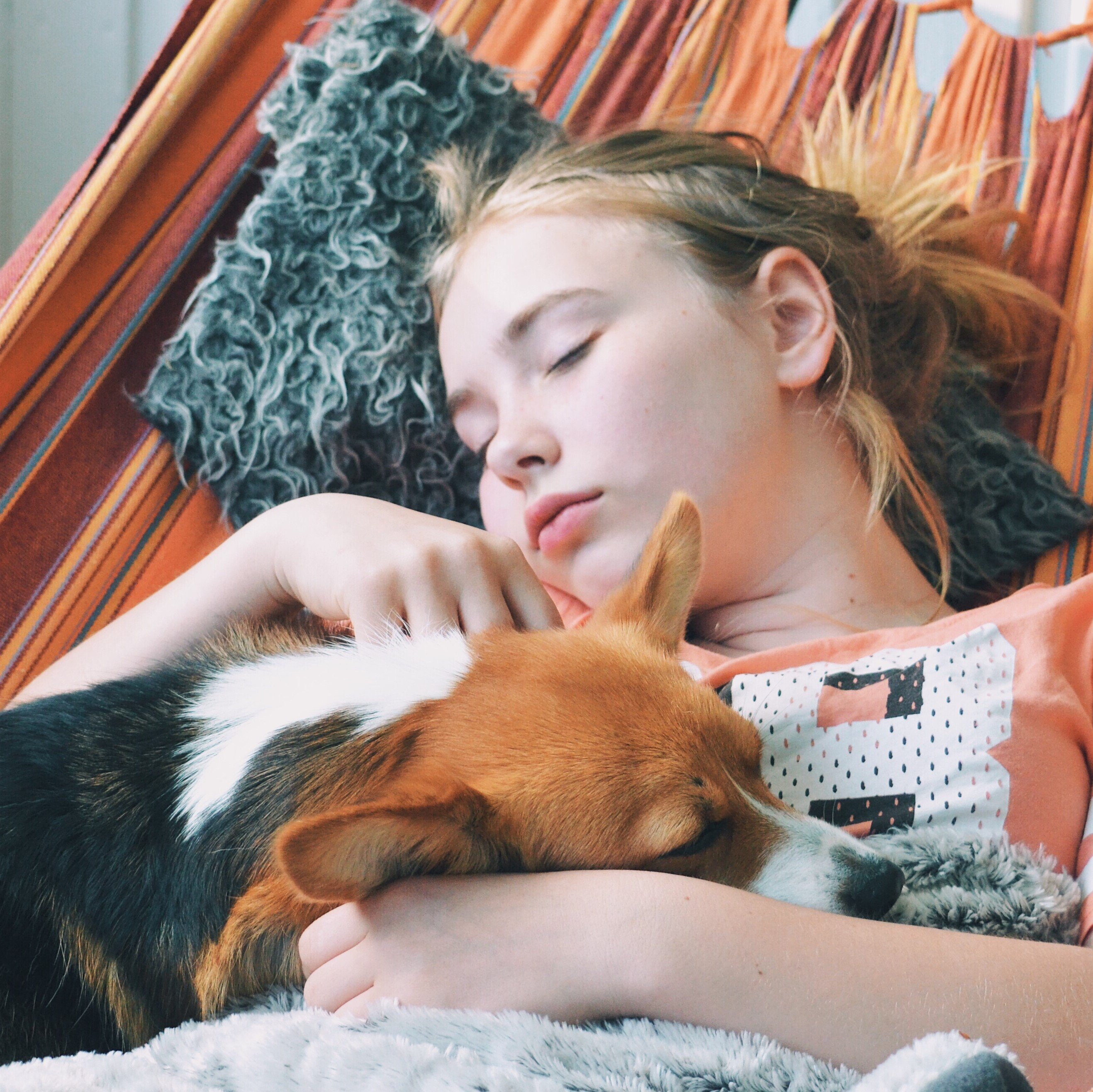 Menina deitada em uma rede e um cachorro deitado ao seu lado