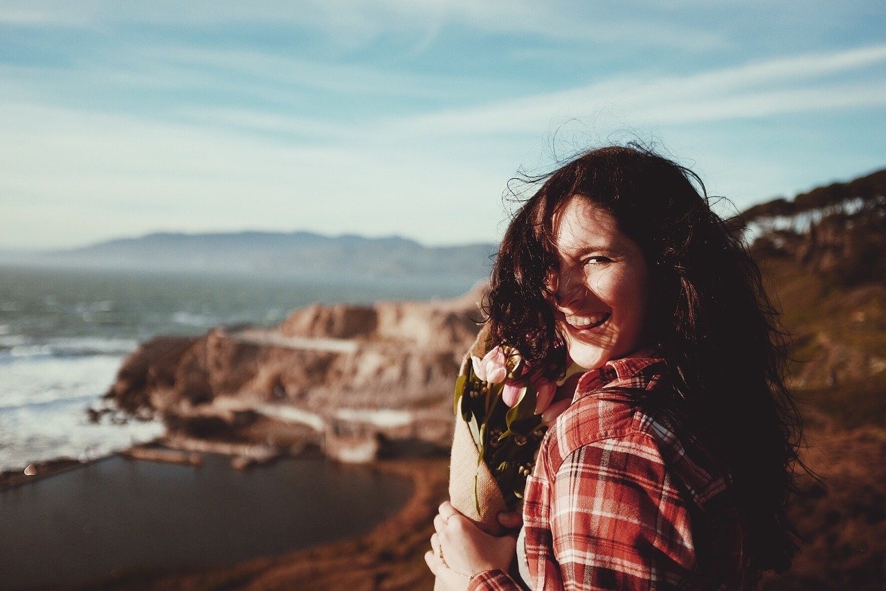 Mulher sorrindo ao lado de uma montanha