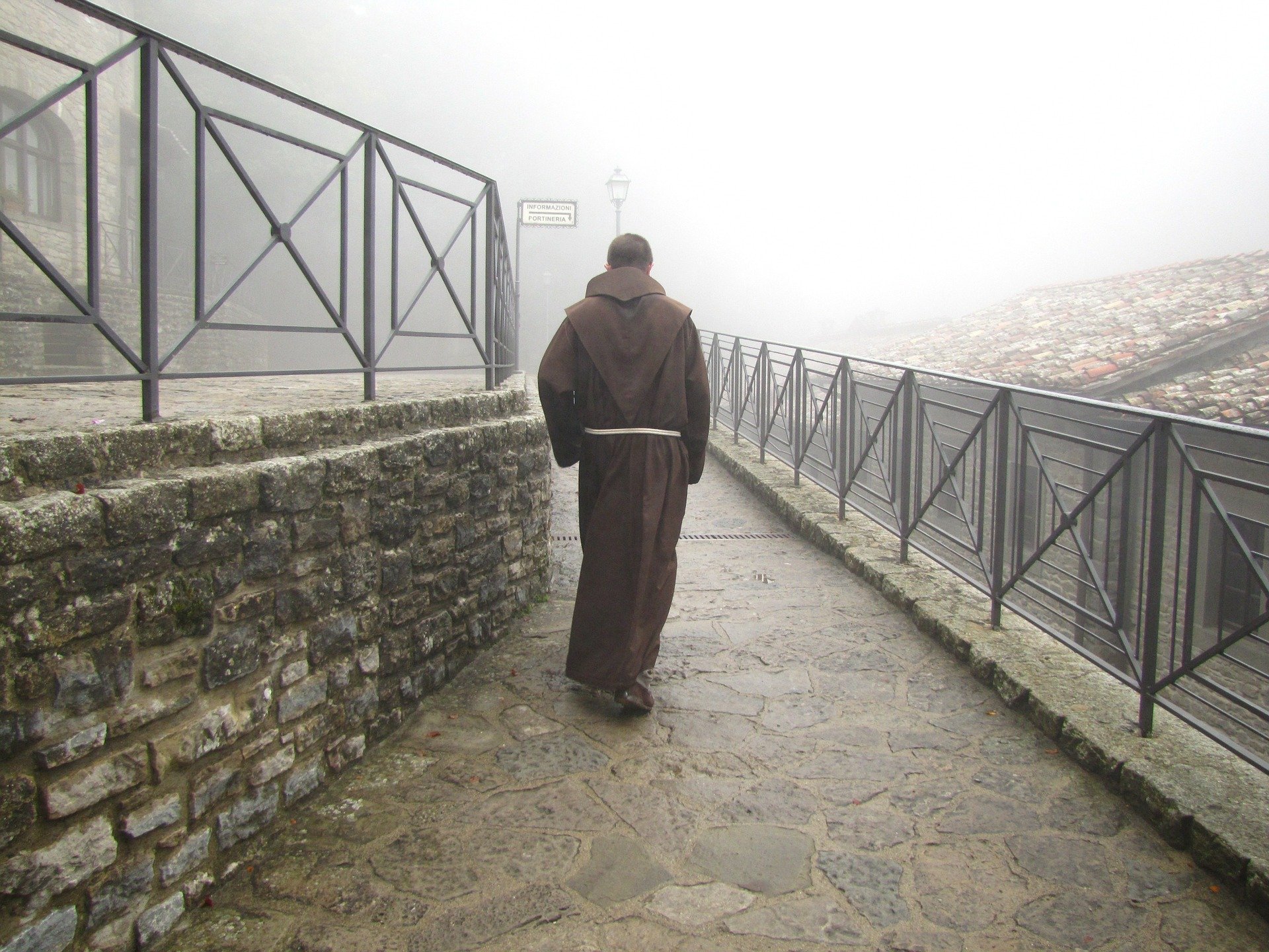 Homem com vestes tradicionais cristãs eremitas andando sobre uma ponte