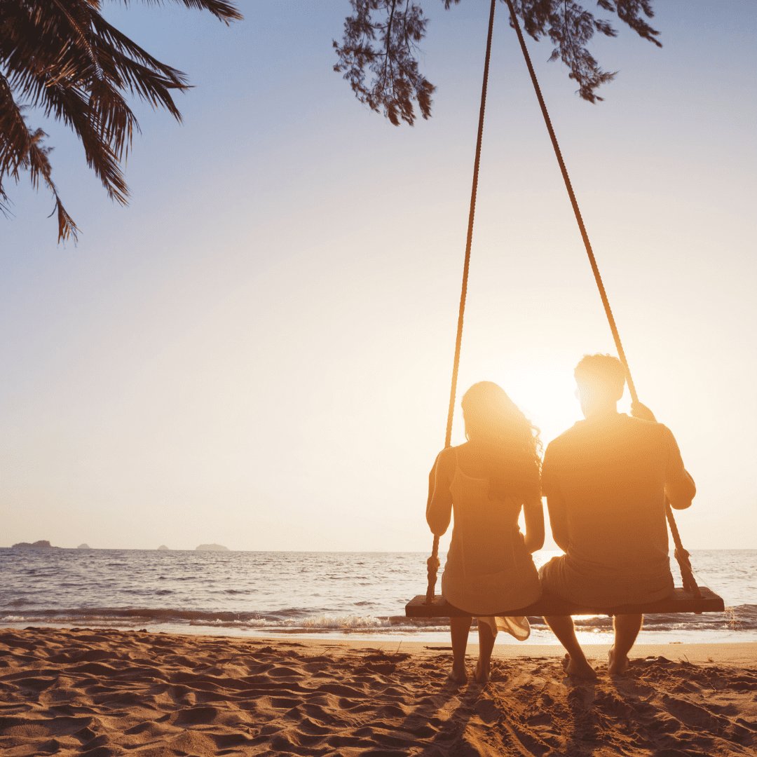 Silhueta de casal sentados no balanço da praia