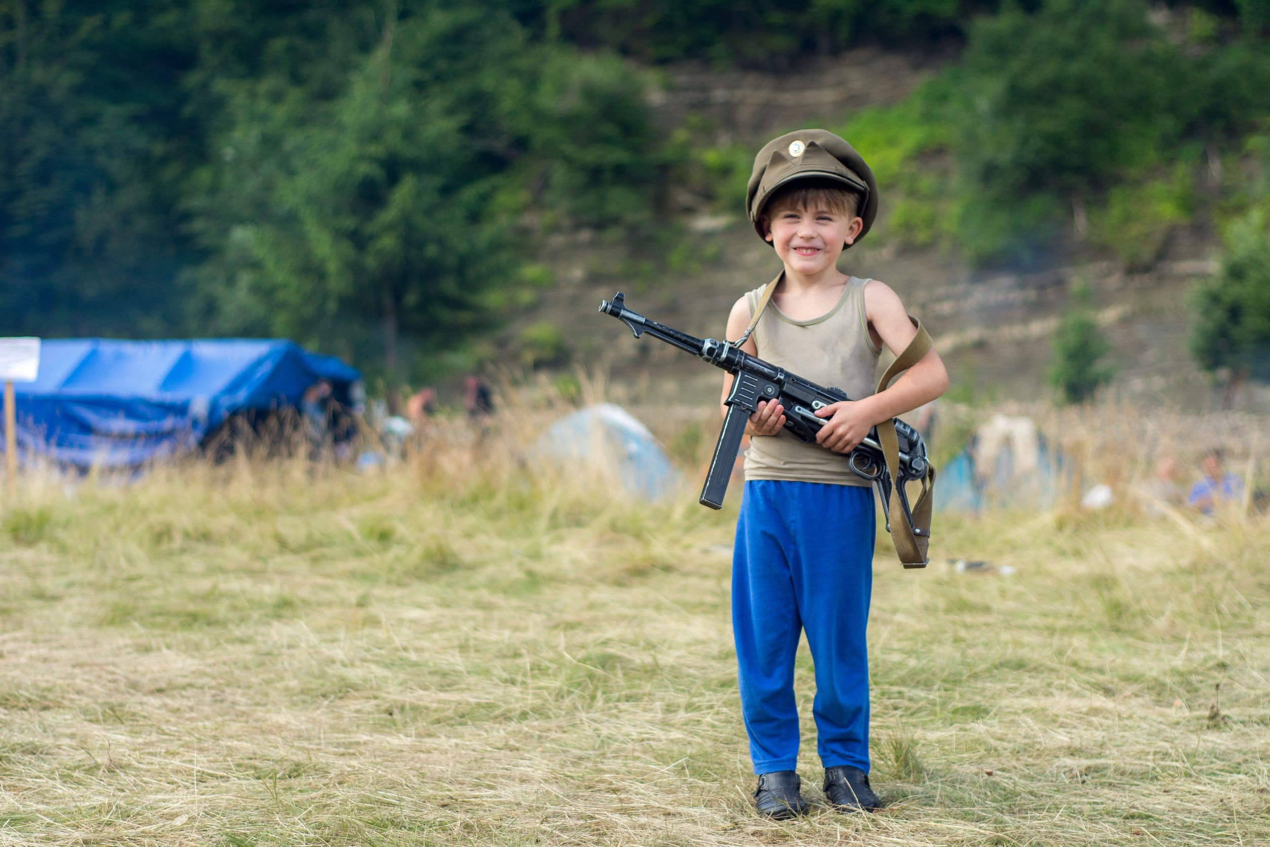 Criança segurando uma arma e sorrindo