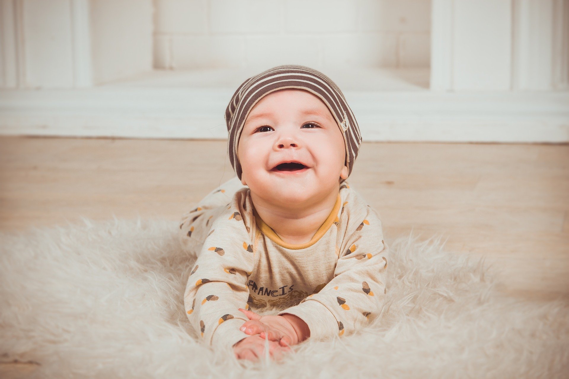Bebê de barriga para baixo no chão sorrindo