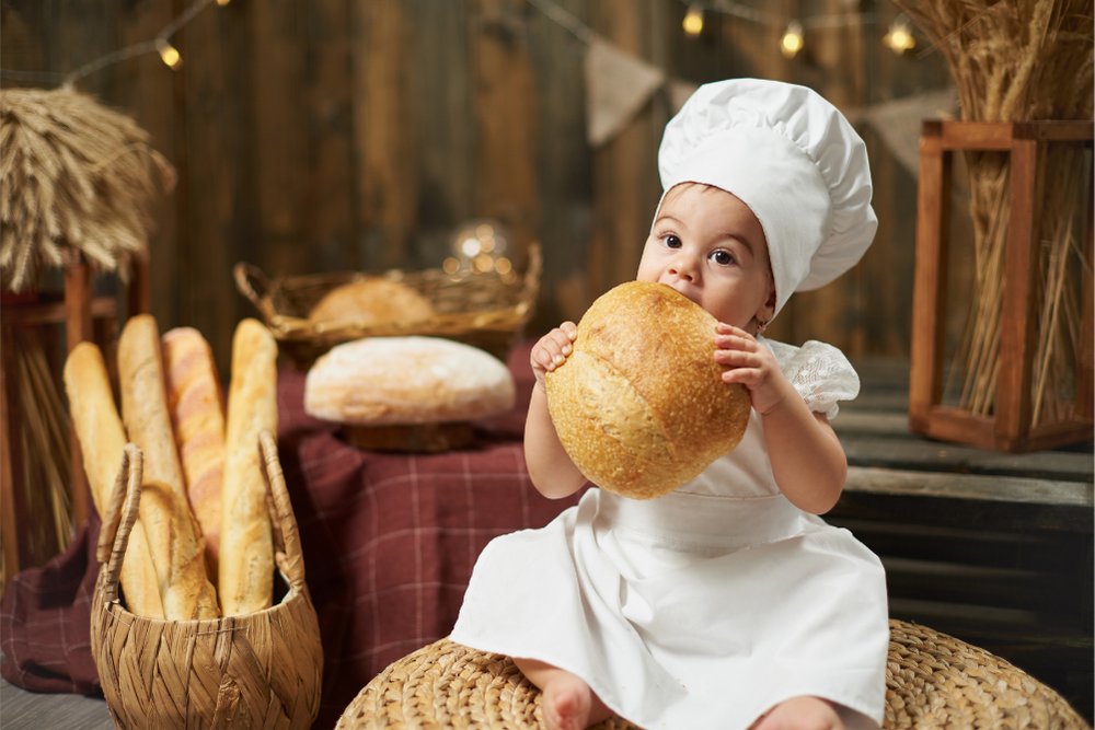 Bebê vestido de chefe de cozinha em cenário temático de pães