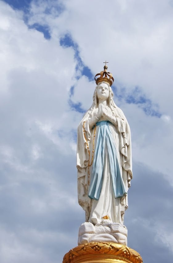 Estátua de Nossa Senhora a céu aberto, em local alto.