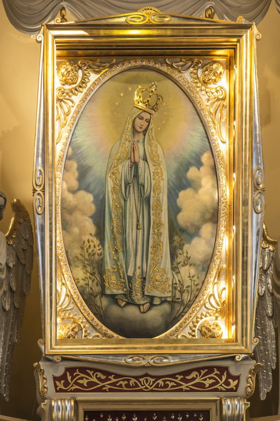 Imagem de Nossa Senhora, com moldura de ouro, no altar de uma igreja.