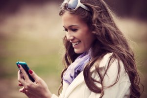 Mulher olhando para celular sorrindo