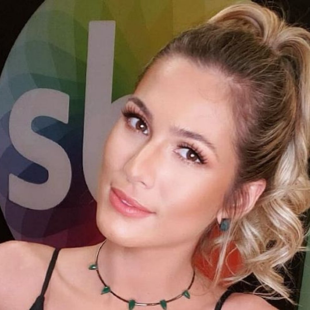 Imagem da apresentadora Lívia Andrade tirando uma selfie com o logo do SBT atrás