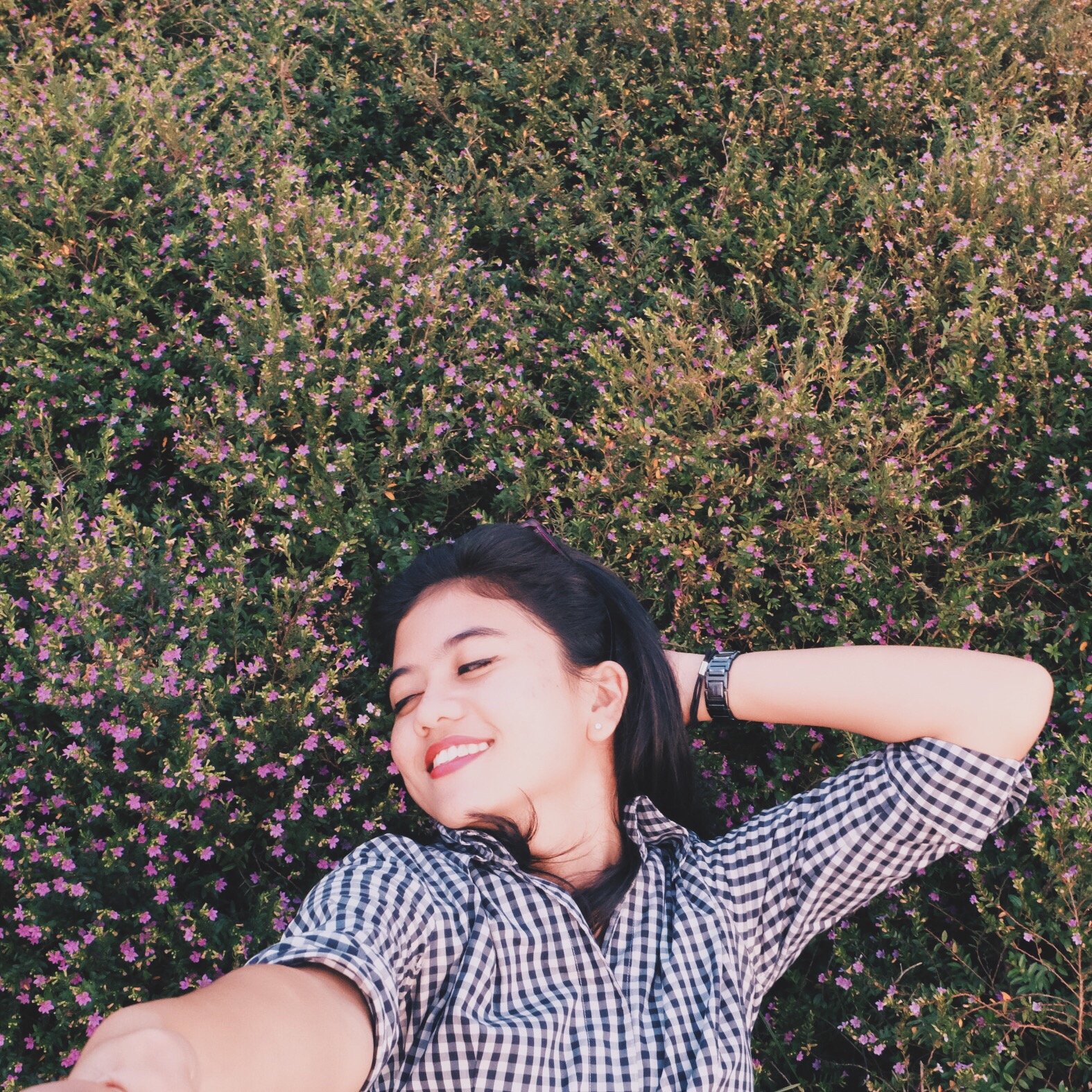 Mulher sorrindo deitada em um gramado com os olhos fechados