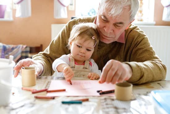 Avô com sua neta no colo que está desenhando com giz de cera