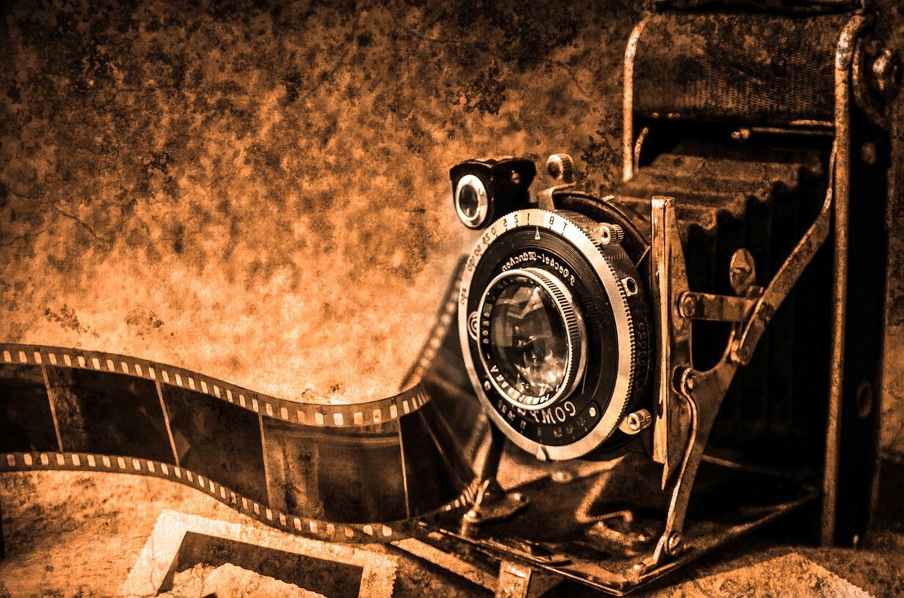 Uma câmera antiga. Ao lado, o filme dela está esticado.
