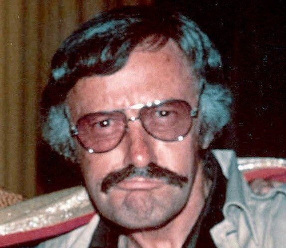 Stan Lee jovem, de bigode e óculos, nos anos 70