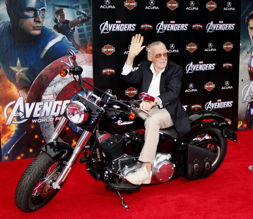 Stan Lee posando para foto montado em moto cenográfica