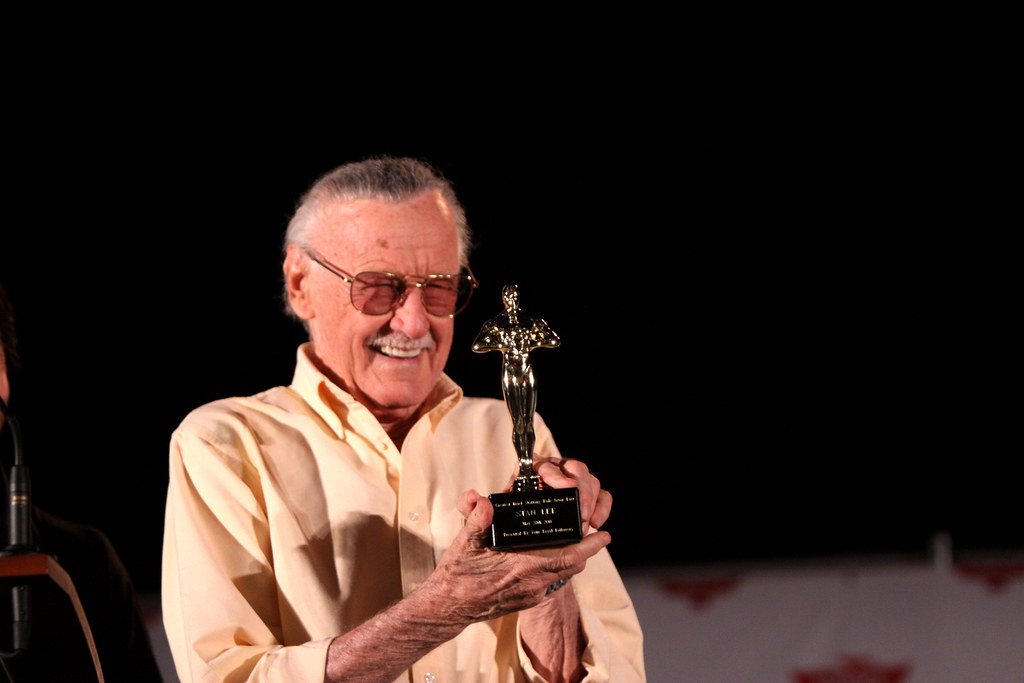 Stan Lee sorridente segurando um troféu