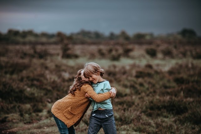Menino e menina brancos se abraçando num campo escuro