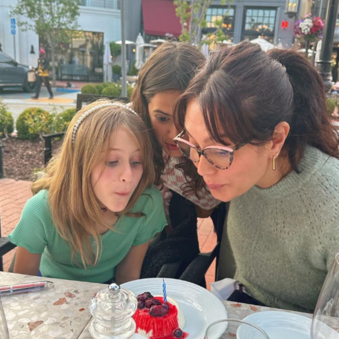 Emma com filhas soprando velinhas de um cupcake