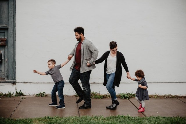 Família de mãe, pai e duas crianças caminhando