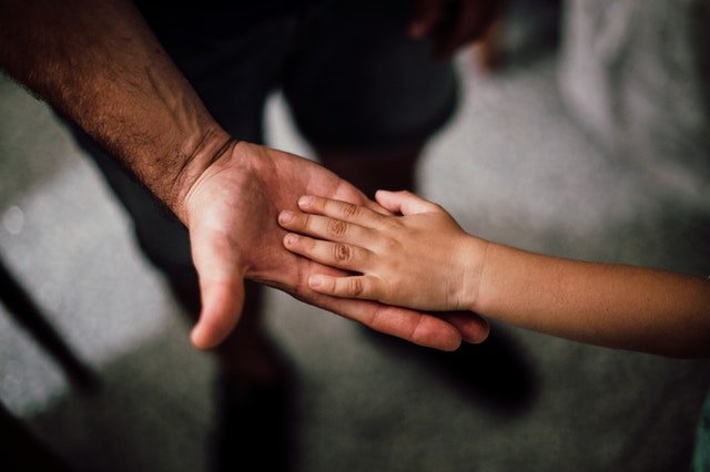 Mão de uma criança sobre a mão de um adulto