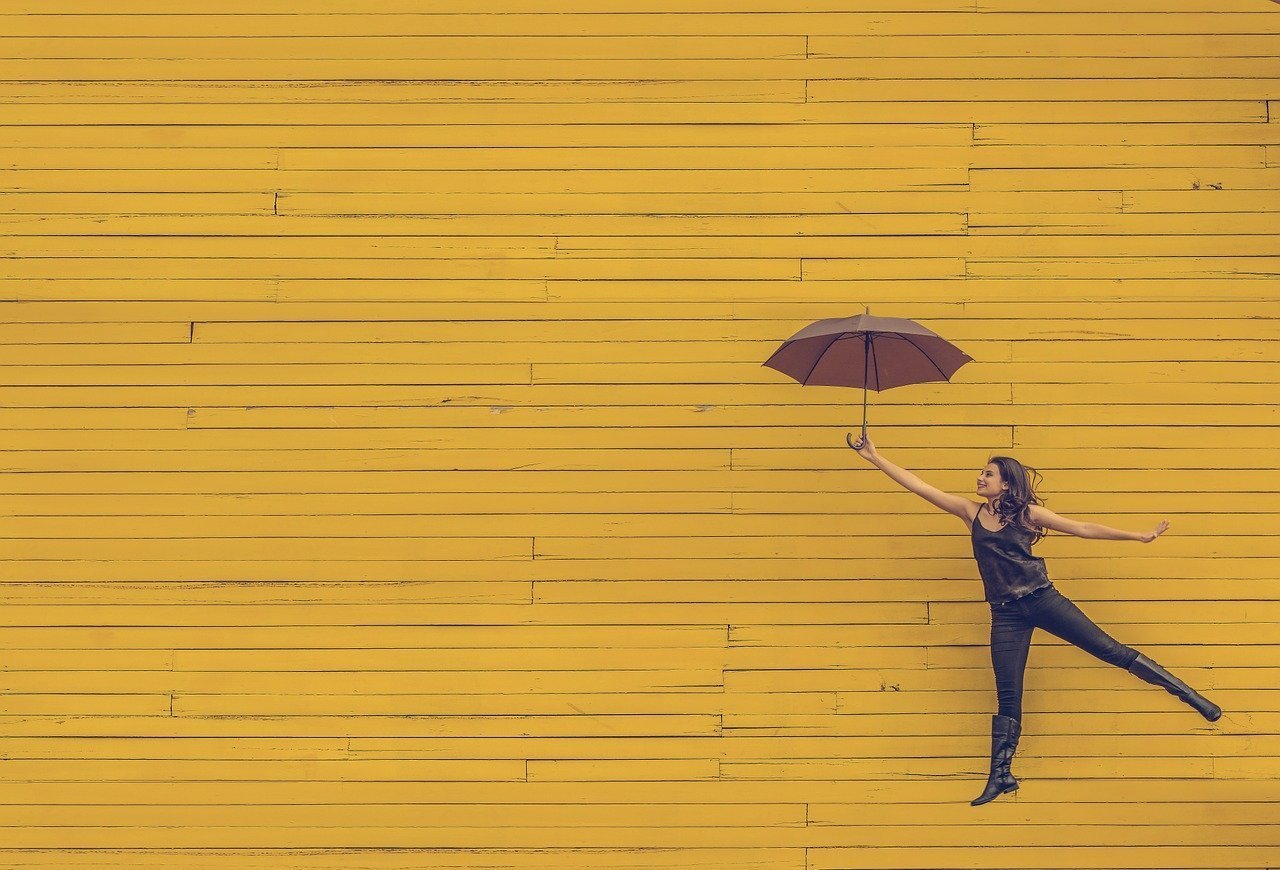 Mulher posando com guarda chuva na frente de fundo amarelo