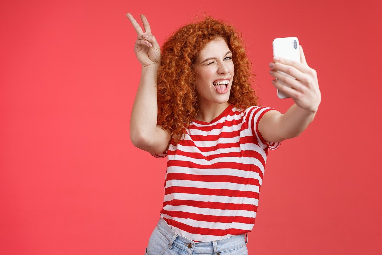 Mulher ruiva posando para selfie divertida