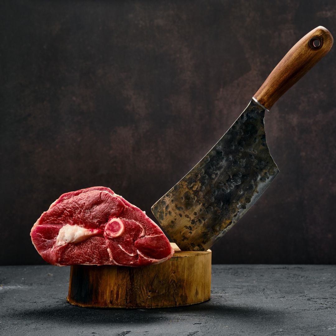 Pedaço de carne e facão em cima de uma tábua