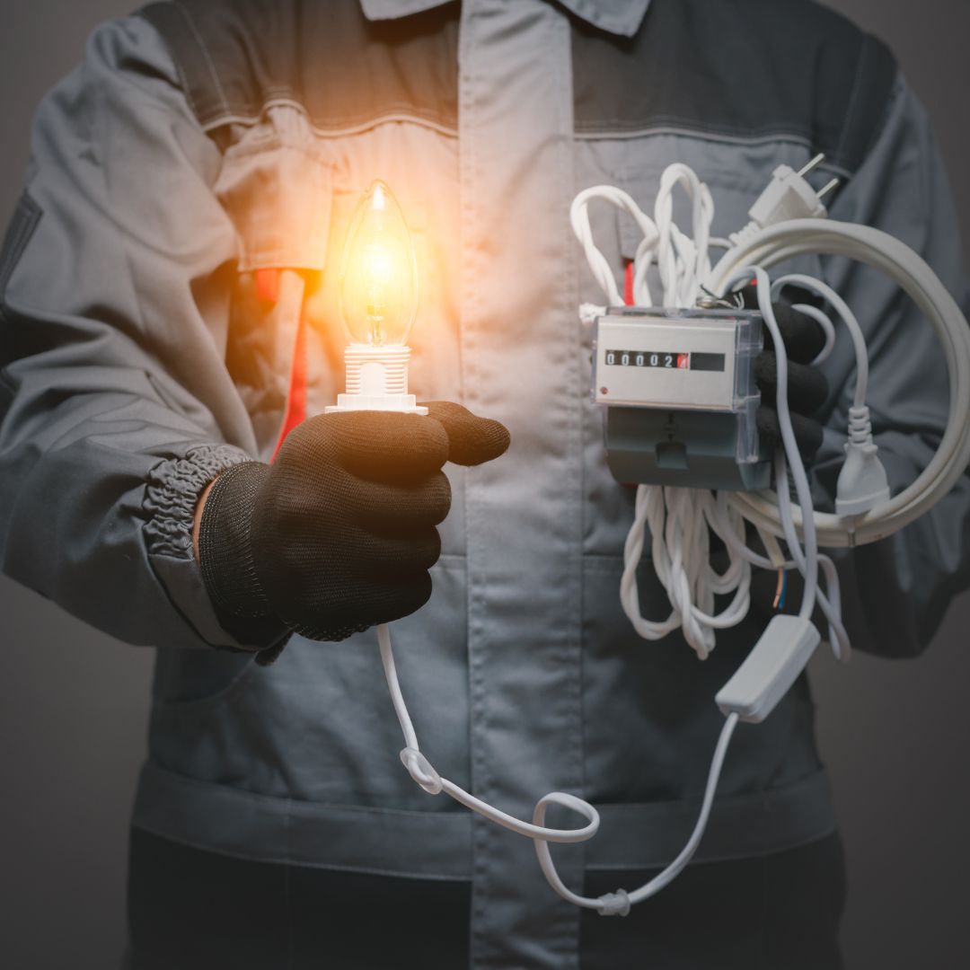 Eletricista segurando lâmpada acesa e medidor de energia