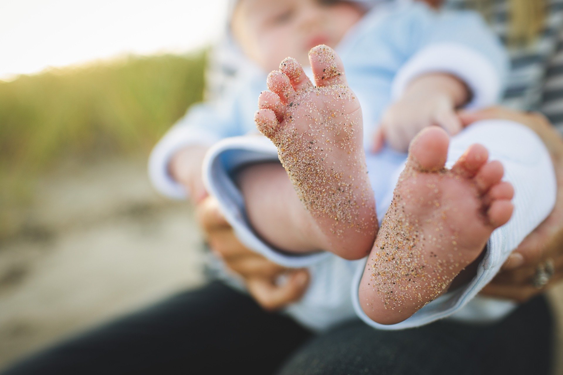 Pés de bebê com areia da praia