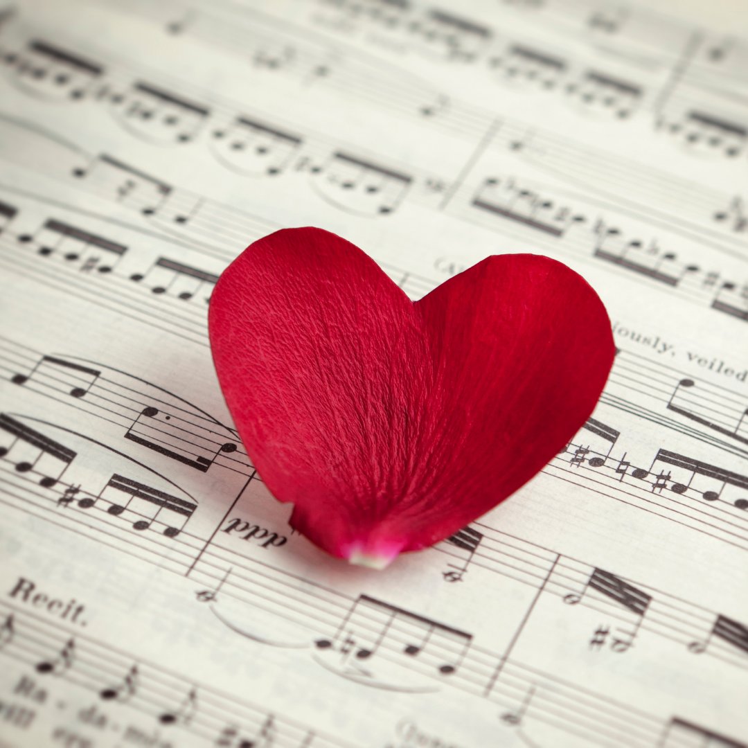 Foto de duas pétalas formando um coração em cima de uma partitura musical