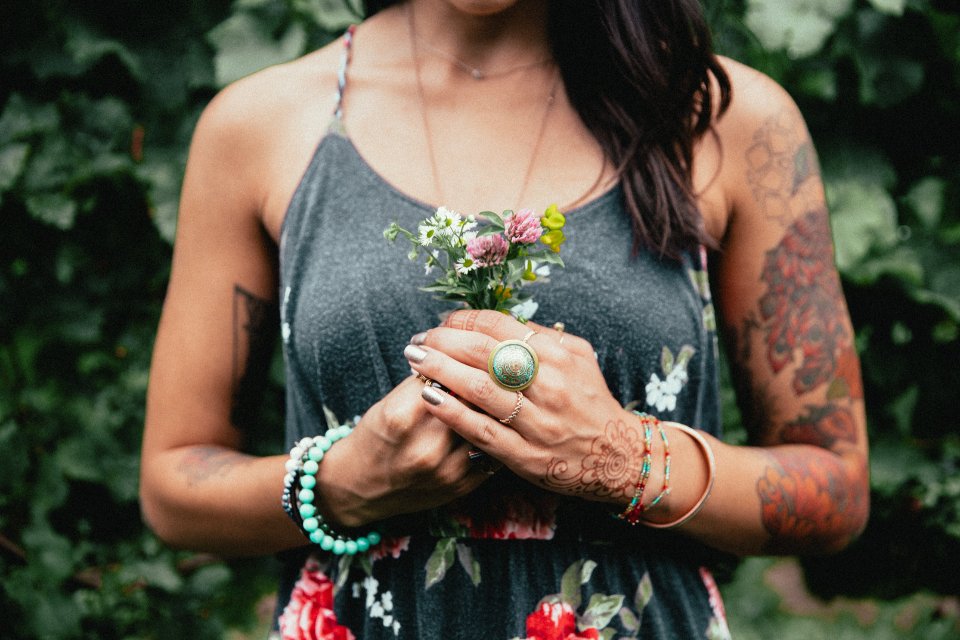 Mãos de mulher segurando flores em frente ao peito