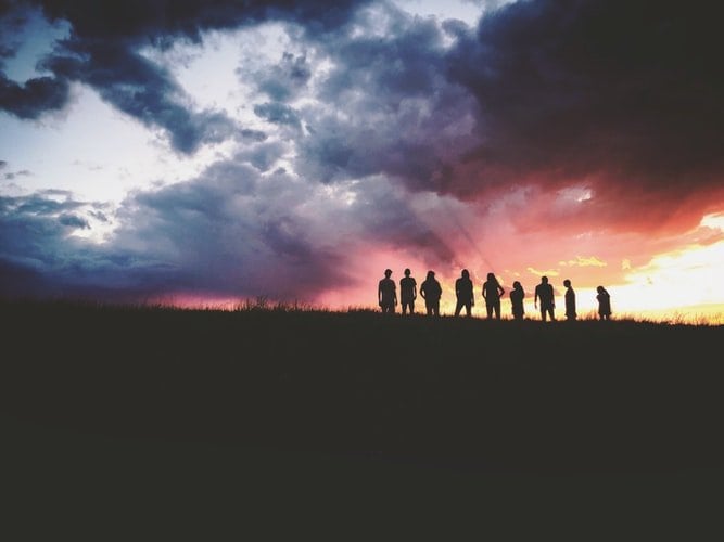Silhueta de nove pessoas frente a um pôr do sol