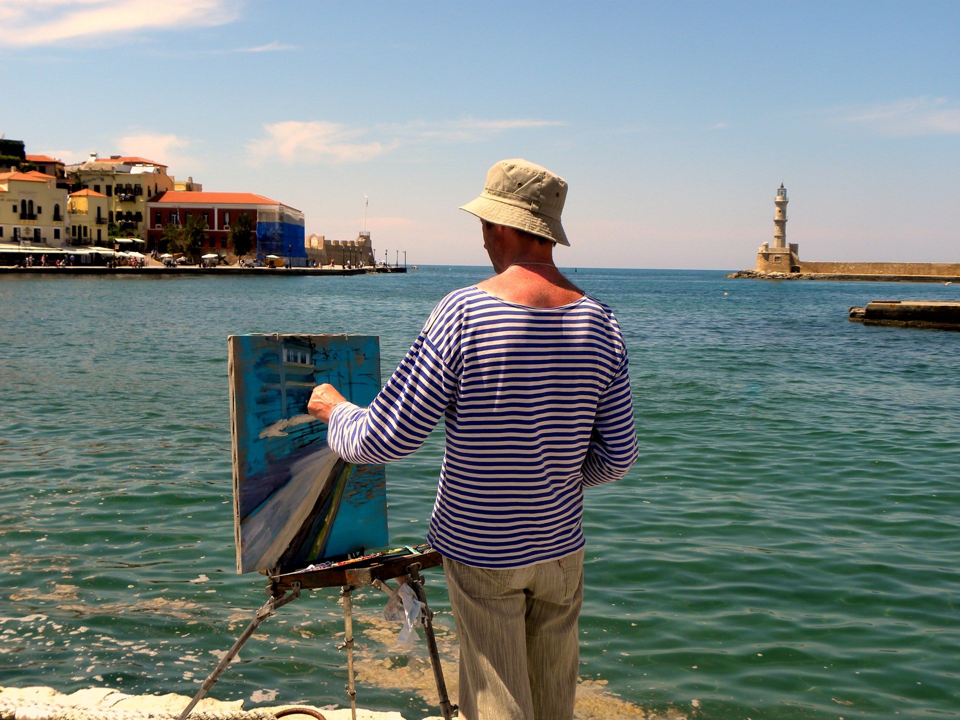 Homem pintando quadro em frente ao mar