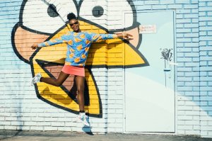 Mulher pulando na frende de muro com grafite