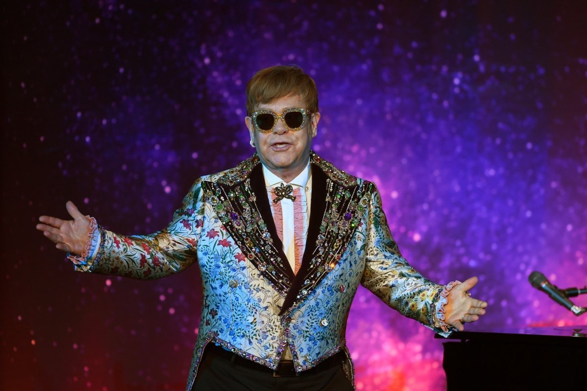 Elton John em show, usando blazer azul claro coberto de pedras